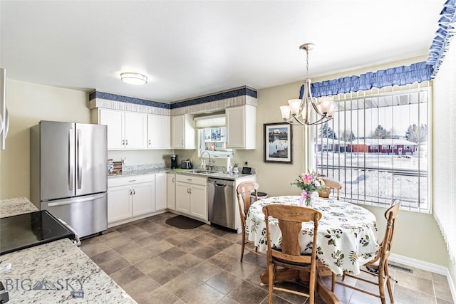 kitchen featuring baseboards, an inviting chandelier, a sink, white cabinets, and appliances with stainless steel finishes