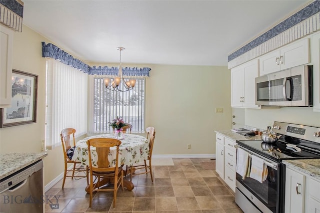 kitchen featuring light stone counters, baseboards, stainless steel appliances, white cabinets, and a notable chandelier