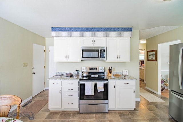 kitchen with white cabinets, light stone countertops, and stainless steel appliances