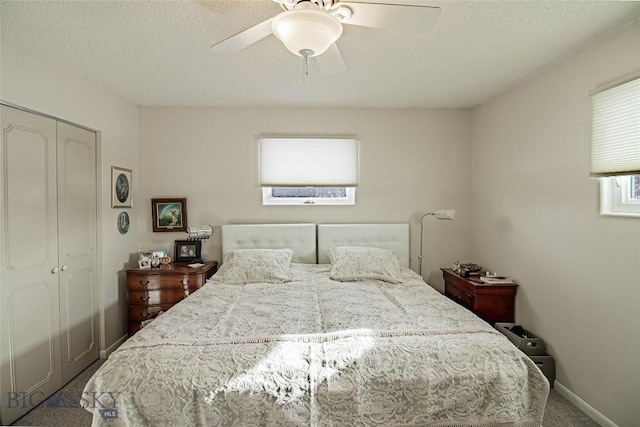 bedroom featuring baseboards, carpet, a closet, a textured ceiling, and a ceiling fan