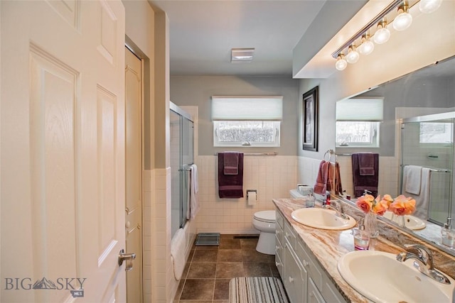 bathroom featuring tile patterned floors, toilet, double vanity, and a sink