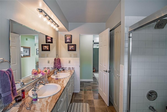 bathroom with tile walls, tiled shower, and a sink