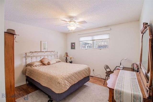 bedroom featuring baseboards, a textured ceiling, wood finished floors, and a ceiling fan