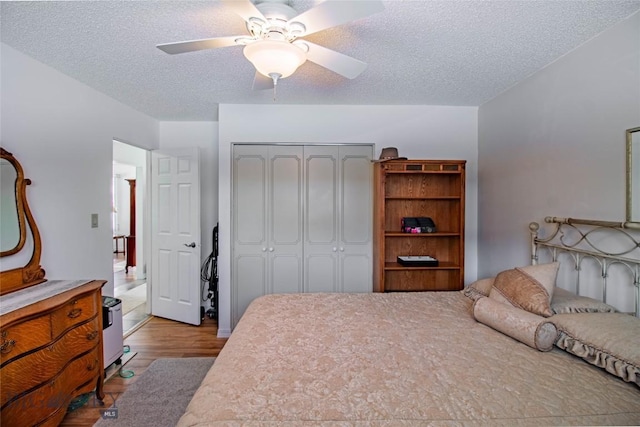 bedroom featuring ceiling fan, a closet, a textured ceiling, and wood finished floors