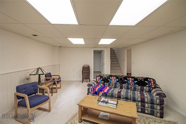 sitting room featuring a drop ceiling and stairs