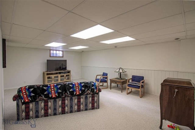 interior space with carpet, a drop ceiling, and wainscoting