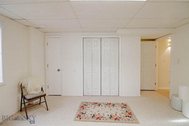 living area featuring a paneled ceiling, baseboards, and carpet floors