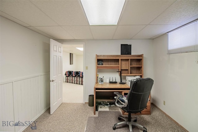 carpeted office with a paneled ceiling and wainscoting