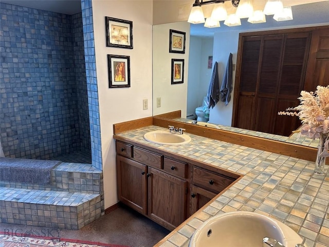 bathroom with a tile shower, a notable chandelier, toilet, and vanity