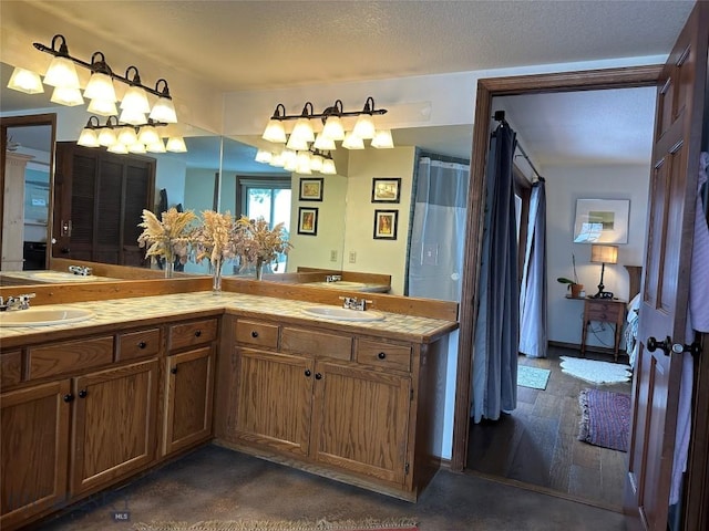 full bath featuring double vanity, wood finished floors, a textured ceiling, and a sink