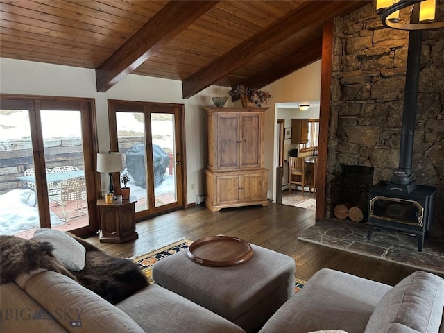 living area featuring vaulted ceiling with beams, wood ceiling, a wood stove, dark wood-style floors, and a notable chandelier