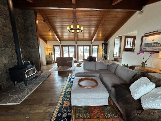 living room with hardwood / wood-style flooring, a wood stove, a notable chandelier, and wooden ceiling