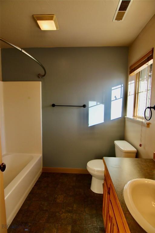 bathroom featuring visible vents, baseboards, toilet, bathing tub / shower combination, and vanity