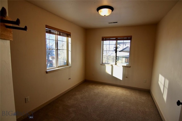 carpeted empty room featuring visible vents and baseboards