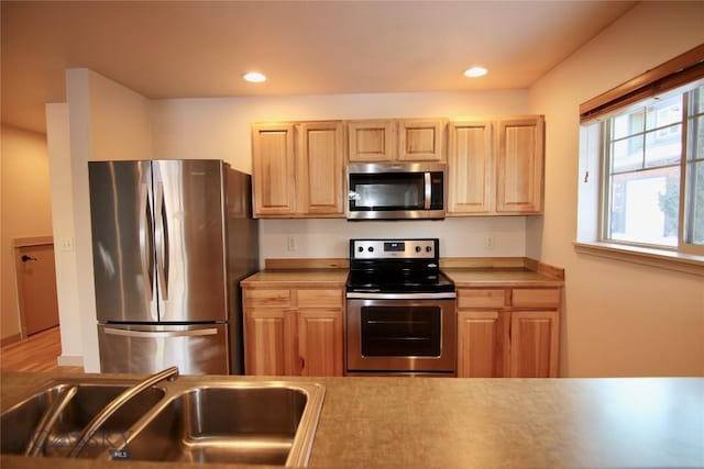 kitchen featuring light brown cabinets, recessed lighting, a sink, light countertops, and appliances with stainless steel finishes