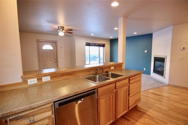 kitchen with a sink, a glass covered fireplace, recessed lighting, light wood finished floors, and dishwasher