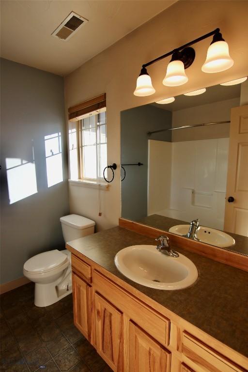 bathroom featuring visible vents, a shower, toilet, and vanity