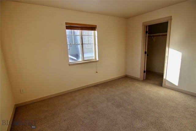 unfurnished bedroom featuring baseboards, carpet floors, and a walk in closet