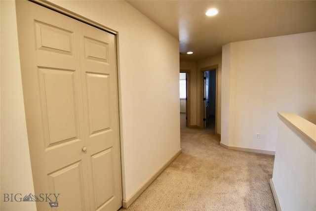 hallway with recessed lighting, light colored carpet, and baseboards