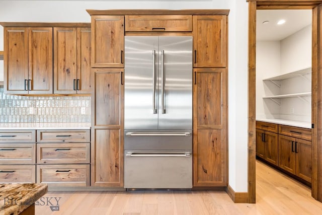 kitchen with light wood finished floors, brown cabinetry, stainless steel built in fridge, and open shelves