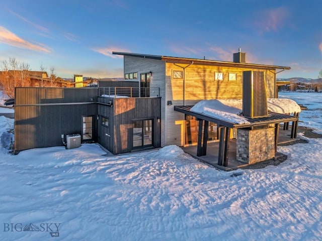 snow covered house with a patio and a balcony