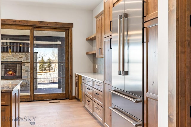 33 Leachman Ln, Bozeman, MT 59718 - kitchen with high end refrigerator, light wood-type flooring, open shelves, and a stone fireplace