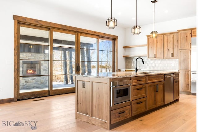 kitchen featuring tasteful backsplash, visible vents, light wood-type flooring, and a sink