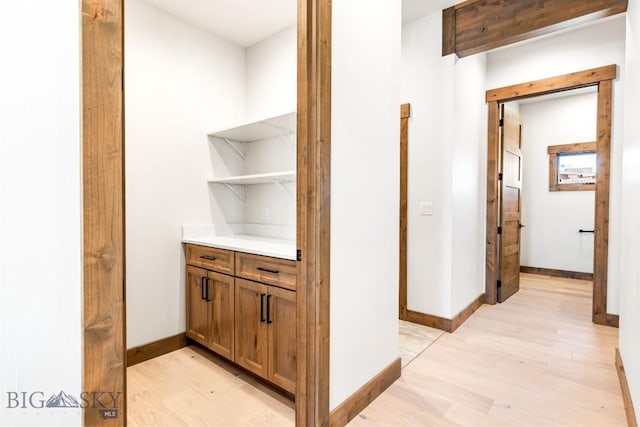 hallway featuring light wood finished floors and baseboards