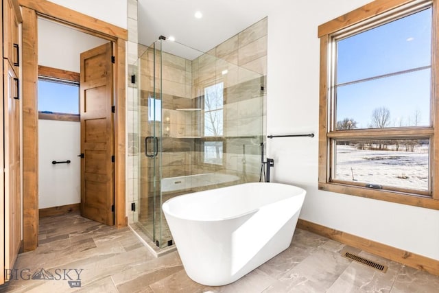 full bathroom featuring visible vents, baseboards, a soaking tub, and a shower stall