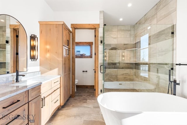 bathroom with a shower stall, a freestanding bath, toilet, marble finish floor, and vanity