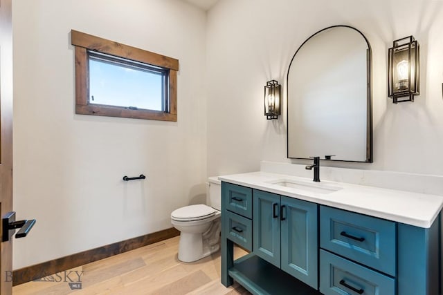 bathroom with baseboards, toilet, wood finished floors, and vanity