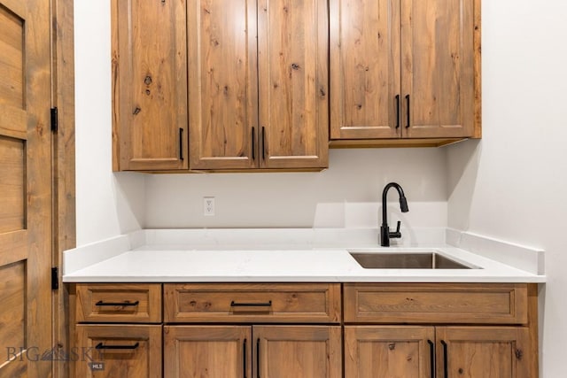 kitchen featuring brown cabinetry, light countertops, and a sink