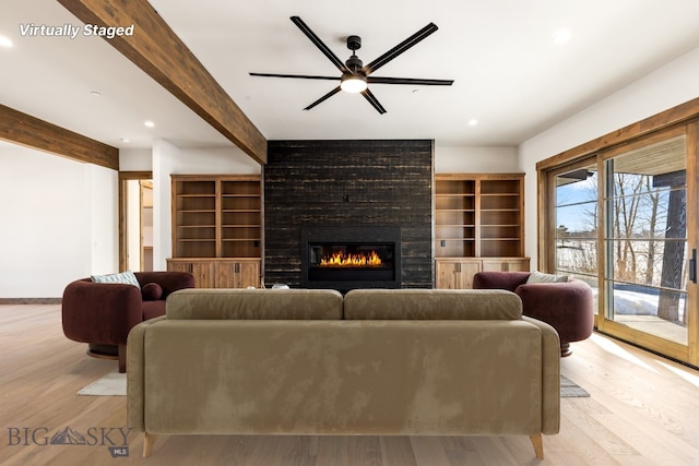 living room with beam ceiling, ceiling fan, a fireplace, and light wood-style floors