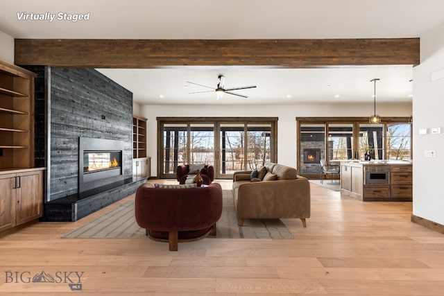 living room featuring recessed lighting, a large fireplace, beam ceiling, and light wood finished floors