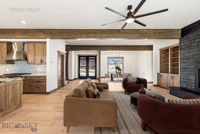 living area featuring light wood finished floors, a fireplace, baseboards, beamed ceiling, and ceiling fan