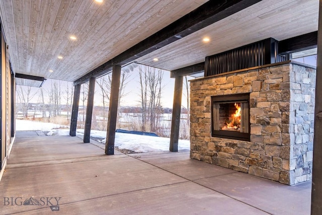 snow covered patio featuring a stone fireplace