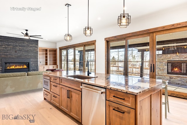 kitchen with a ceiling fan, a sink, open floor plan, a glass covered fireplace, and dishwasher