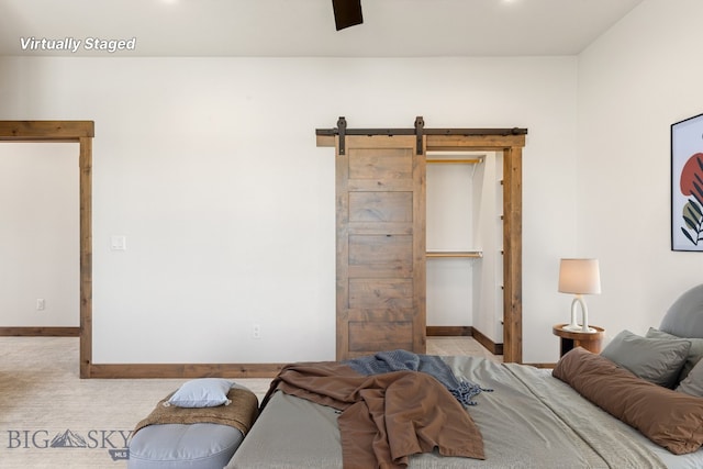 carpeted bedroom with baseboards, a barn door, and ceiling fan