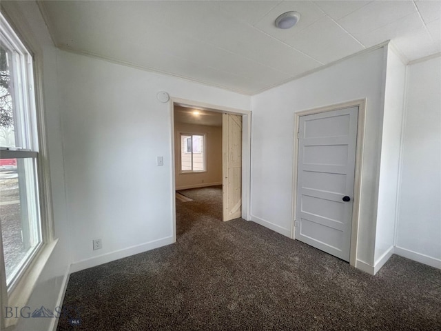 spare room featuring baseboards and dark colored carpet