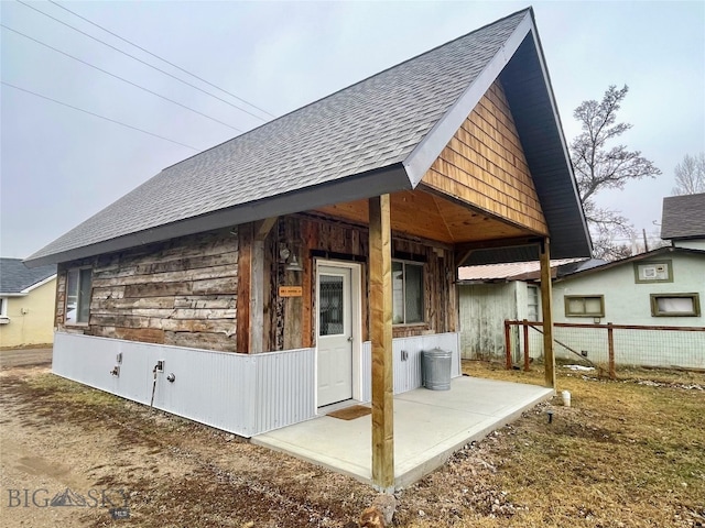 exterior space with roof with shingles and fence