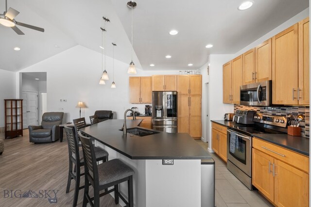 2465 Lasso Ave, Bozeman, MT 59718 - kitchen featuring stainless steel appliances, dark countertops, open floor plan, a kitchen bar, and tasteful backsplash