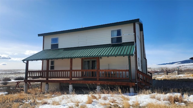 snow covered house featuring metal roof and a porch