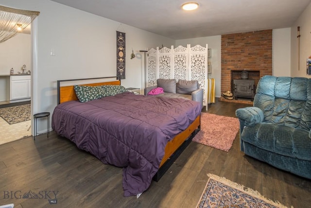 bedroom featuring dark wood finished floors, a wood stove, and a sink