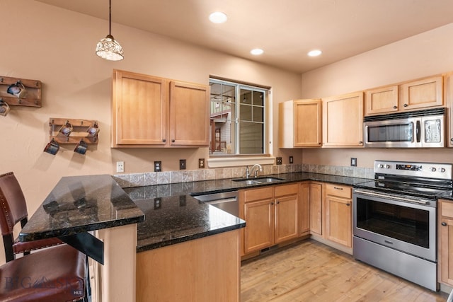 2236 Gallatin Green Blvd Unit C, Bozeman, MT 59718 - kitchen featuring appliances with stainless steel finishes, light brown cabinetry, a sink, a peninsula, and light wood finished floors