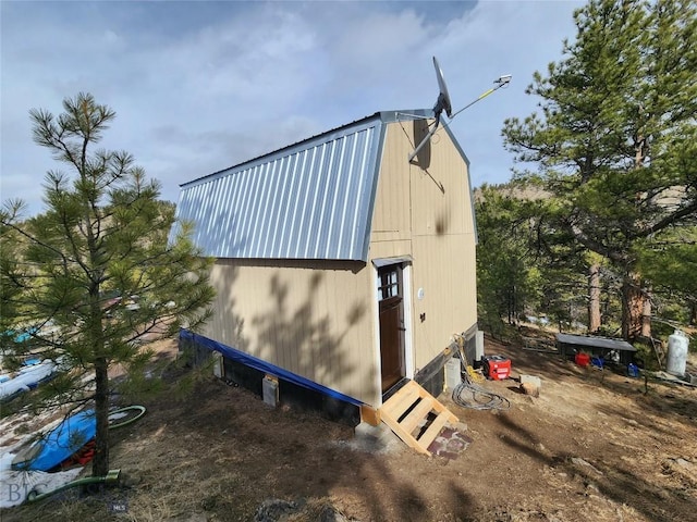view of home's exterior with an outdoor structure, a gambrel roof, and metal roof