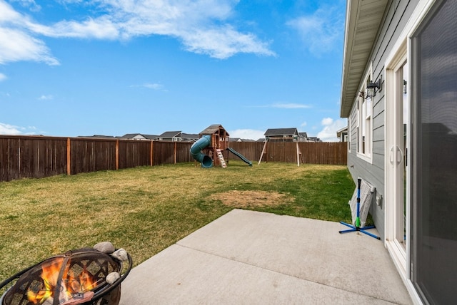 view of yard featuring a fire pit, a fenced backyard, a patio, and a playground