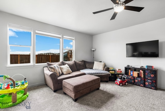 carpeted living area with baseboards and ceiling fan