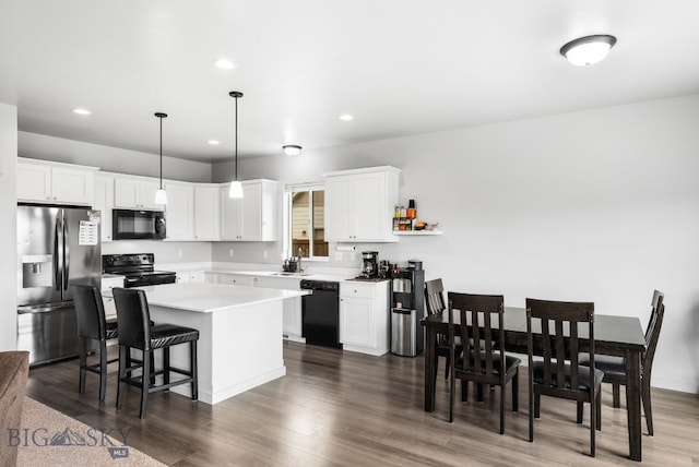 kitchen with a sink, white cabinetry, light countertops, a kitchen island, and black appliances
