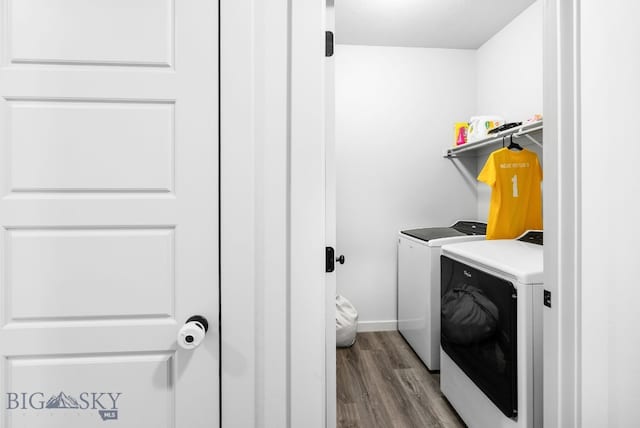 laundry room featuring washing machine and clothes dryer, baseboards, wood finished floors, and laundry area