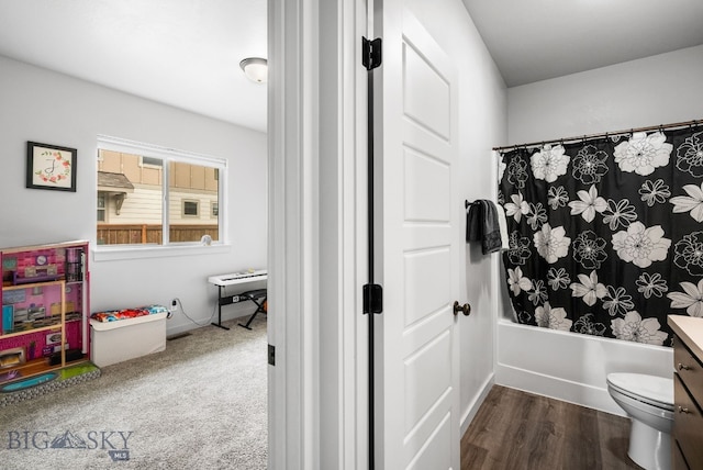 full bathroom with wood finished floors, shower / bath combo, baseboards, and toilet